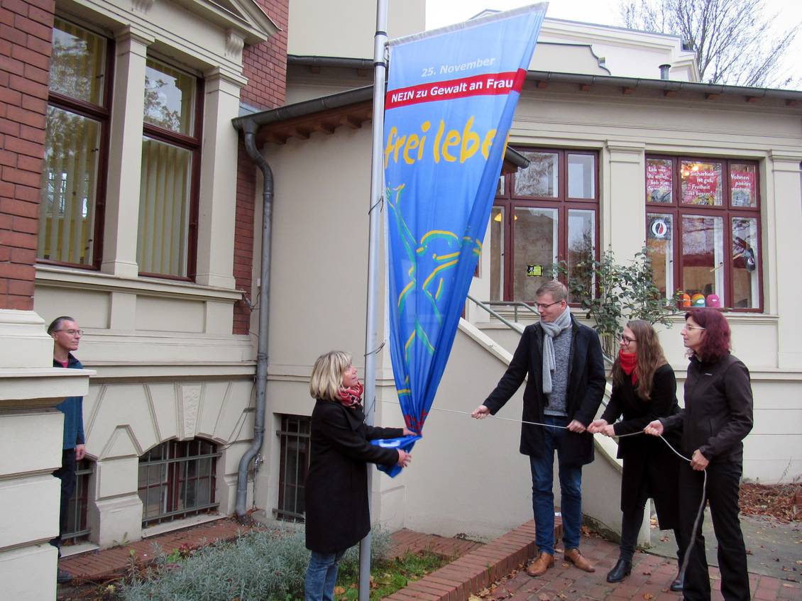 Kathrin Dannenberg, Sebastian Walter, Anja Mayer und Diana Golze hissen gemeinsam die Flagge der Organisation Terre des Femmes mit der Aufschrift "Frei leben – ohne Gewalt"