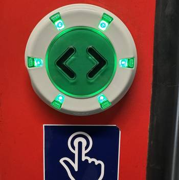 Das Foto zeigt einen grün leuchtenden Türöffner-Knopf in einem Zug.