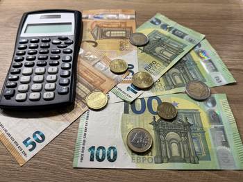 Das Foto zeigt eine Reihe von Euro-Banknoten und Euro-Münzen sowie einen Taschenrechner.