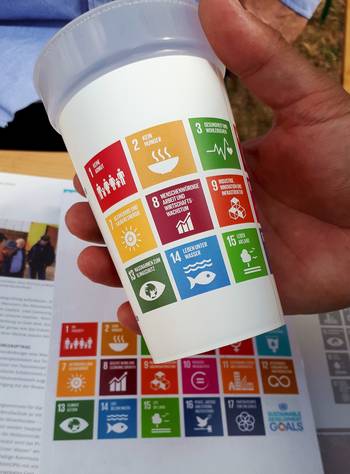 Das Foto zeigt einen Kunststofftrinkbecher, auf dem ein Teil der Nachhaltigkeitsziele der Vereinten Nationen aufgedruckt sind.