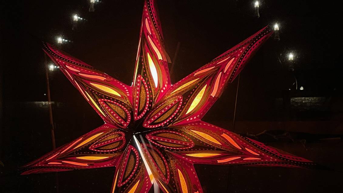 Das Foto zeigt einen beleuchteten Weihnachtsstern und Schwibbogen bei Nacht.