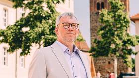 Das Foto zeigt Jochen Neumann auf dem Boulevard in Luckenwalde, im Hintergrund ist der Marktturm zu sehen.
